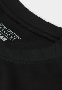 Černé bavlněné tričko s hladkým límečkem a jemným švem, se bílým označením "Premium Cotton" a názvem značky.