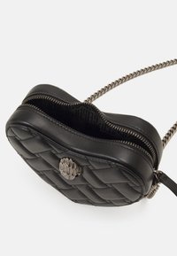 Borsa a tracolla in pelle nera trapuntata con tracolla in catena argentata, dotata di chiusura con zip e logo decorativo in metallo sulla parte frontale.