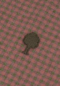 Tessuto di stoffa in rosa tenue con un motivo a quadri verde e grigio. Presenta una decorazione ricamata a forma di albero verde.