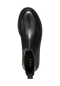 Stivale chelsea in pelle nera presenta una finitura liscia, dettagli brogue lungo la punta, pannelli laterali elastici e una suola texturizzata.