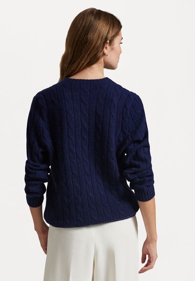 Pull en maille côtelée bleu marine avec un col rond et des manches longues, présentant des poignets côtelés et un ourlet arrondi pour une coupe décontractée.