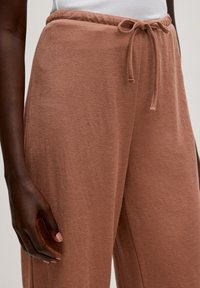 Lichtbruine, losse broeken met een trekkoord in de taille, gemaakt van zachte stof, met een gladde textuur en een wijd pootontwerp.