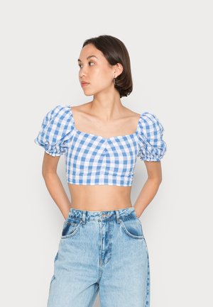 Top cropped em padrão xadrez azul e branco com mangas bufantes, decote quadrado e detalhes franzidos, combinado com calças jeans altas de cintura clara.