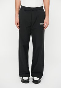 Crne, lagane, sužene hlače s elastičnom trakom u struku, s kopčom i malim "Double" logotipom na lijevoj strani.