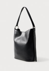 Bolso tote de cuero negro con una textura suave, forma redondeada y una única correa para el hombro. Acento de metal plateado en la correa.