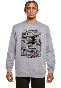 Sivá mikina s komiksovým štýlom grafiky, s výraznými čiernymi a červenými prvkami. Dlhé rukávy, rebrované manžety a lem.