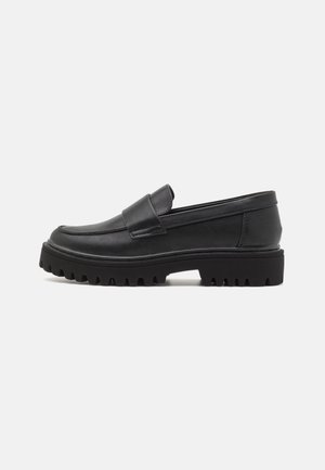 Sorte læderloafers med lav profil, gummisål med zigzagmønster og en bred rem foran for ekstra detalje.