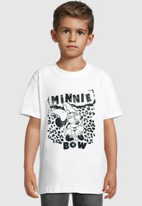T-shirt en coton blanc avec un graphique noir représentant un personnage de dessin animé avec un nœud, entouré d'un motif léopard et de texte en gras.