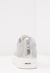 Metalen zilveren sneaker met een gladde textuur, afgeronde vorm, witte rubberen zool, decoratief stiksel en een merkaccent op de hiel.
