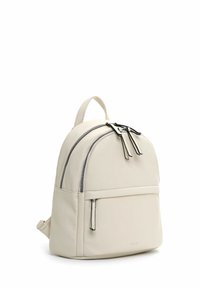 Petit sac à dos en cuir crème avec deux compartiments principaux zippés, une poche frontale zippée et une poignée supérieure.