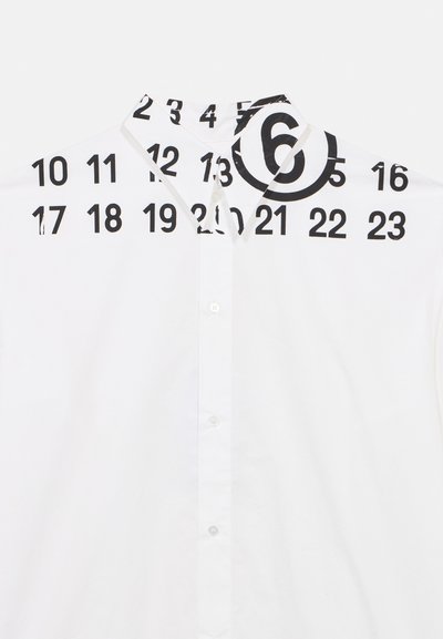 Λευκό πουκάμισο με ψηλό γιακά, κλείσιμο με κουμπιά και έντονα μαύρα νούμερα και κύκλους τυπωμένα στο πάνω μέρος.