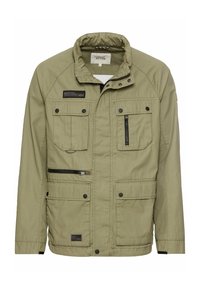 Olive green jacket made of fabric, featuring a high collar, multiple pockets, and a zippered front closure. Textured surface with branded patch.