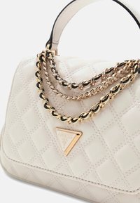 Sac à main blanc matelassé avec des accents de chaîne or et noir, présentant une plaque de logo triangulaire. Texture en cuir lisse et forme structurée.