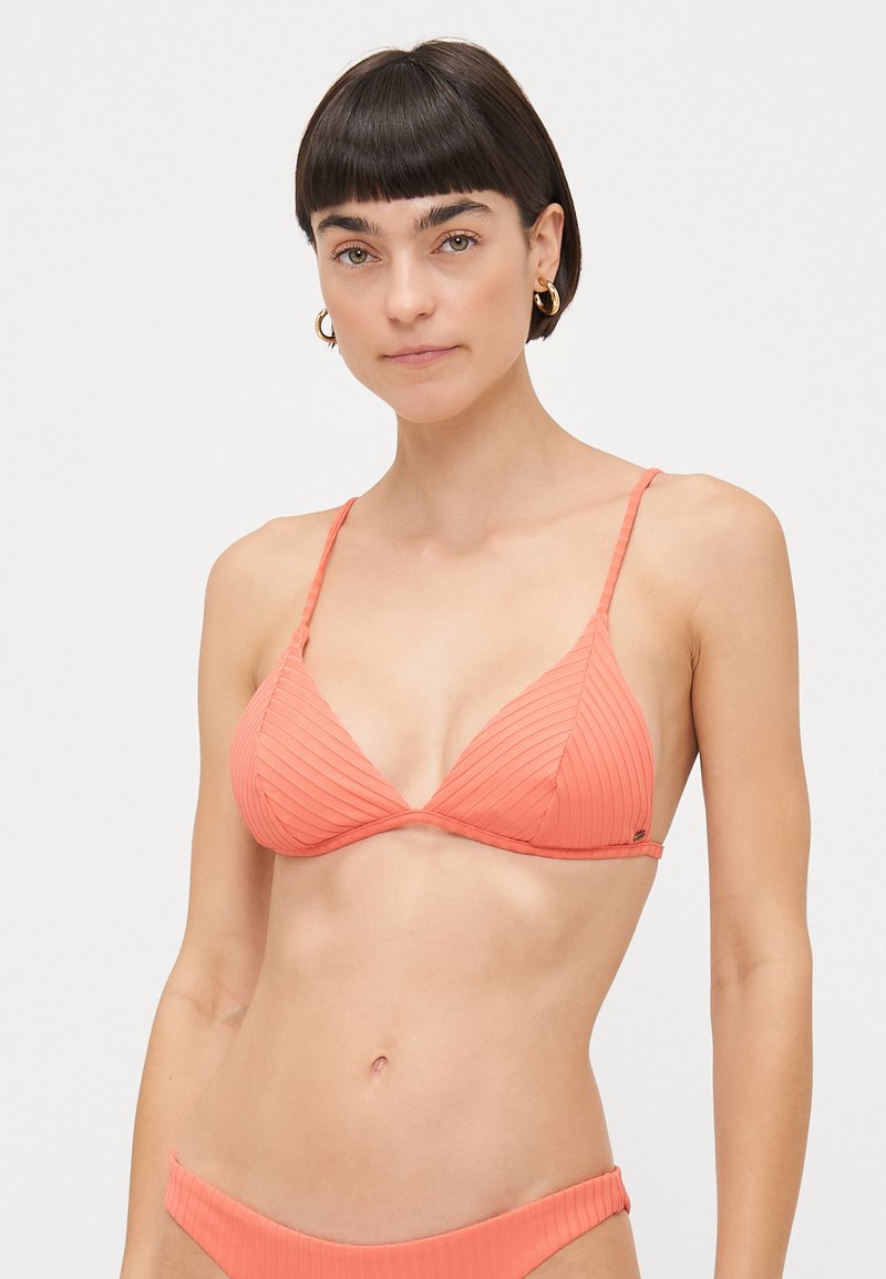 Korala tanga bikini s trokutastim dizajnom, tankim podesivim trakama i bešavnom završetkom, prikazujući minimalistički izgled i teksturu.