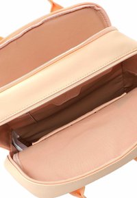 Borsa color pesca con una finitura liscia e opaca. L'interno presenta una fodera in tessuto morbido, una tasca con zip e un compartimento aperto per lo stoccaggio.