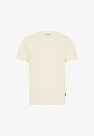 T-shirt à manches courtes et col rond en beige clair, tissu texturé avec un petit logo sur la poitrine et une étiquette sur le côté.
