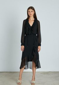Schwarzes, gerafftes Kleid mit durchsichtigen langen Ärmeln und V-Ausschnitt. Es hat einen geschichteten, asymmetrischen Saum und eine Kordelzug-Taille.