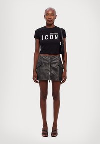Black cropped t-shirt with "ICON" text, paired with a gray leather mini skirt featuring a front zipper and pocket details.