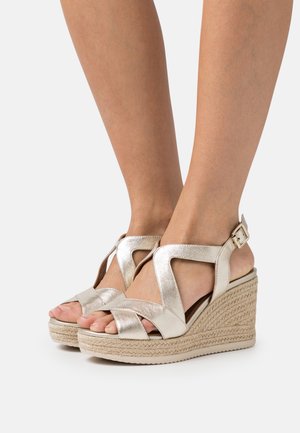 Sandales à plateforme en biais avec une finition dorée métallique, dotées de brides entrecroisées et d'une plateforme en jute tressé. Boucle sur la bride de cheville pour un maintien sûr.