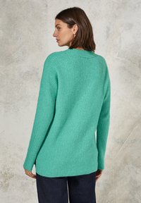 Maglione lavorato a maglia di un turchese chiaro con una vestibilità ampia, caratterizzato da una trama a coste e un collo rotondo, abbinato a pantaloni scuri.