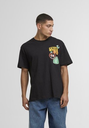 Must musta t-särk, millel on värvilised paigad: "TRUE RELIGION" kollases, punane ringikujuline logo ja rohelised detailid. Lühikesed varrukad, mugav lõige.