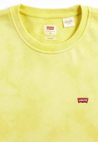 Gele Levi's t-shirt met ronde hals, zachte textuur en subtiel tie-dye patroon. Heeft een klein rood geborduurd logo op de linkerkant van de borst.