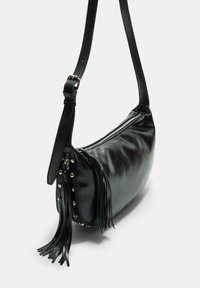 Schwarze Leder-Schultertasche mit runder Form, Reißverschluss, dekorativen Fransen und Metallnieten an einer Seite. Verstellbarer Trageriemen inklusive.