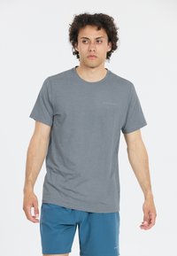 Harmaa crew-neck t-paita pehmeästä kankaasta, jossa on lyhyet hihat ja huomaamaton logo rinnassa. Yhdistetty sinisiin shortseihin.