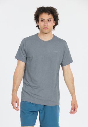 Grå t-shirt med rund hals gjord av mjukt tyg, med korta ärmar och en diskret logotyp på bröstet. Buren med blå shorts.