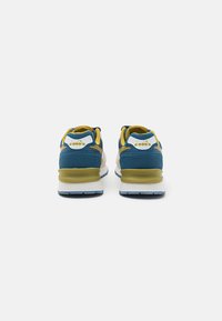 Blue and yellow sneakers with a textured fabric upper and a white midsole, featuring a distinct branding detail on the heel.