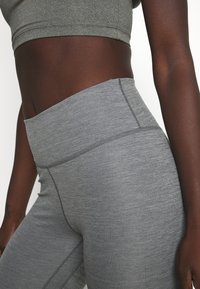 Leggings hautes gris fabriqués en tissu doux et texturé, dotés de coutures plate et d'une ceinture lisse, offrant confort et flexibilité.