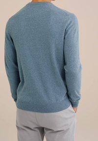 Ljusblå tröja i mjukt stickat material, med rundad halsringning, långa ärmar och ribbade muddar och nederkant bak.