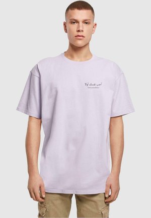 Hellblaue Baumwoll-T-Shirt mit Rundhalsausschnitt; mit bedrucktem arabischen und englischen Text auf der Vorderseite. Kurze Ärmel, lockere Passform.