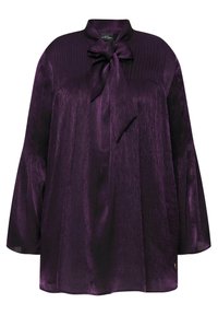 Blusa viola realizzata in tessuto lucido, con collo alto, dettaglio a fiocco, texture a coste e maniche ampie.