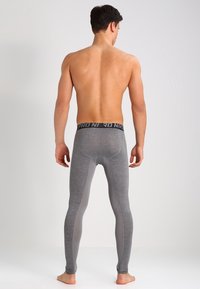 Graue Sportleggings mit einer figurbetonten Passform, ausgestattet mit einem schwarzen Bund mit "PRO"-Markenlogo und kontrastierenden Seitenpanelen in einem helleren Grau.