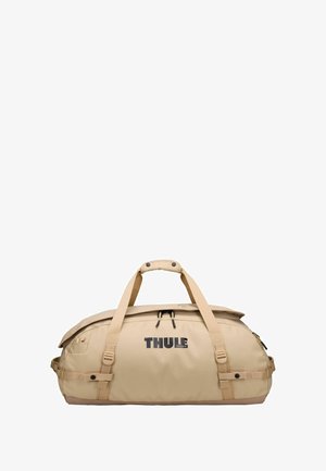 Sac de sport beige avec poignées doubles, poche zippée extérieure, bretelles ajustables et logo 'THULE' bien en vue. Matériau résistant à l'eau et texture lisse.