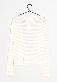 Biały sweter z długim rękawem o poziomej teksturze w paski, wykonany z dzianiny, z szerokim okrągłym dekoltem. Wisi na czarnym wieszaku.