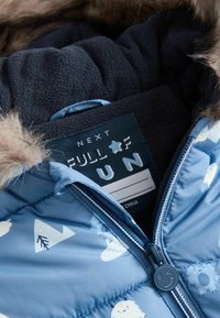 Light blue puffer jacket with white mountain and snowman patterns. Features a fur-lined hood and a dark fleece lining. Zippered front.