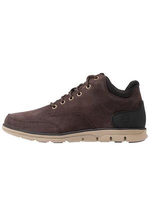 Bruine leren casual veterschoen met beige rubberen zool en zwarte gevoerde kraag, zijaanzicht.