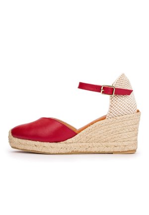 Sandalia de cuña de cuero rojo con puntera cerrada, plataforma de yute tejido, correa en el tobillo con hebilla dorada y contrafuerte del talón beige a cuadros.