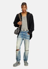 Black and gray plaid shirt layered over a gray tank top, distressed light denim jeans, and gray shoes. Accessories include a gray shoulder bag.