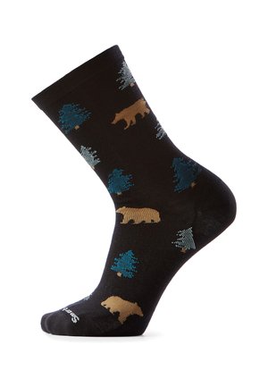 Czarna skarpetka wzorzysta brązowymi niedźwiedziami i niebiesko-zielonymi sosnami, prezentowana na białym tle, z stopą lekko uniesioną do góry.