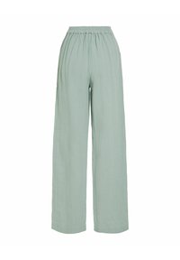 Pantalon large taille haute vert clair avec une ceinture élastique et un tissu doux et texturé.