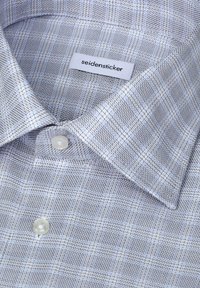 Chemise bleu clair avec un petit motif à carreaux, boutons blancs et une étiquette de la marque seidensticker à l’intérieur du col.