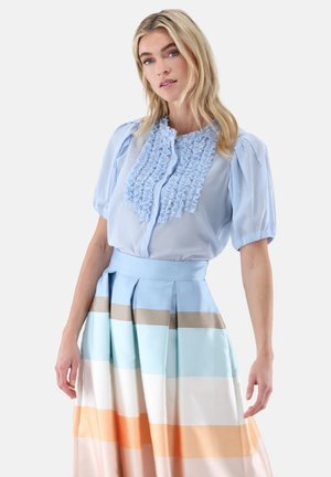 Light blue blouse with ruffled front and short puff sleeves, paired with a multi-striped skirt featuring soft pastel colors and pleats.