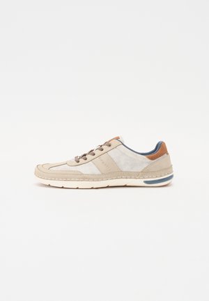 Beige sneakers med overdel i semsket skinn og lerret, med kontrasterende brune detaljer, rund tå, snøring foran og polstret såle med blå detalj.