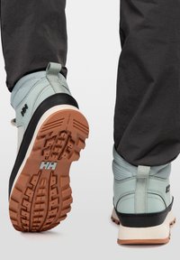 Botas impermeables de media altura en azul claro con detalles en negro y suelas de goma texturizadas. Presentan un tirador y un diseño de banda de rodadura rugosa.
