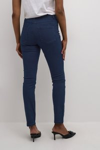 Tmavě modré skinny džíny s vysokým pasem, dvěma zadními kapsami a hladkou denimovou texturou. Nosené s černými podpatkovými mulo.