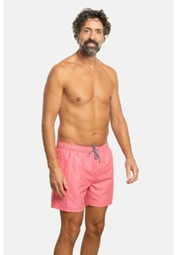 Bañador de hombre en color rosa con cinturilla elástica y cordón. Confeccionado en tela ligera, tiene una textura suave y un corte relajado.