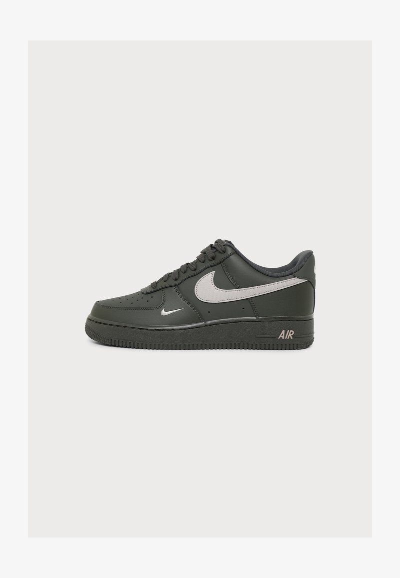 Μαύρο αθλητικό παπούτσι Nike Air Force 1 με γκρι λογότυπα Nike swoosh στο πλάι και κοντά στα κορδόνια, απεικονίζεται από την εξωτερική πλευρά σε λευκό φόντο.